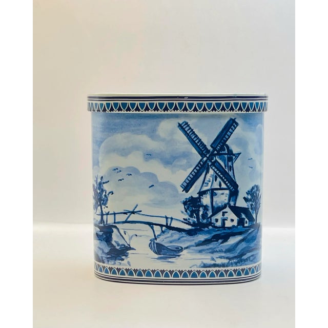 A vintage hinged box featuring a waterside scene with a cottage, windmill and sailing ships.