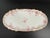An antique Charles Field Haviland celery dish, featuring delicate clusters of pink roses against an embossed, scalloped...