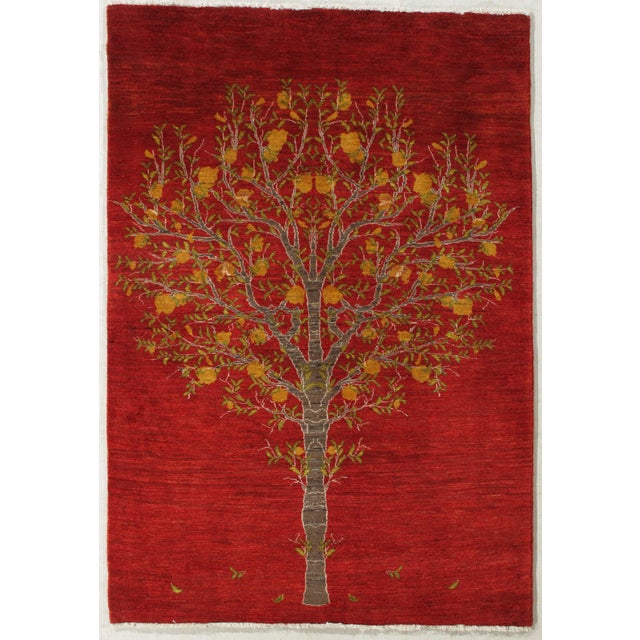 Vintage Hand-knotted Persian Gabbeh wool rug. Red field with a centrally placed tree of life motif, depicting a branching...