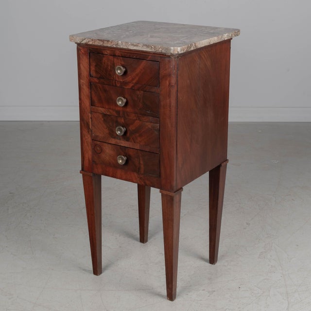 An early 19th century French marble top side table, handcrafted of solid and veneers of mahogany and finished on all four...