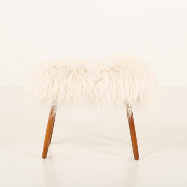 This Danish mid-century stool was made in the late 1960s or early 1970s. It features solid wood legs and is newly...