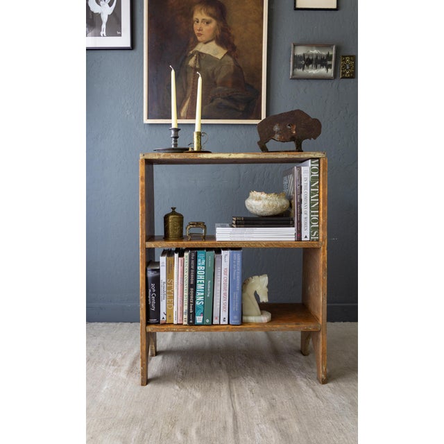 An antique farmhouse bucket-bench-style bookshelf featuring bracket feet defined by graceful ogee arches on each side....