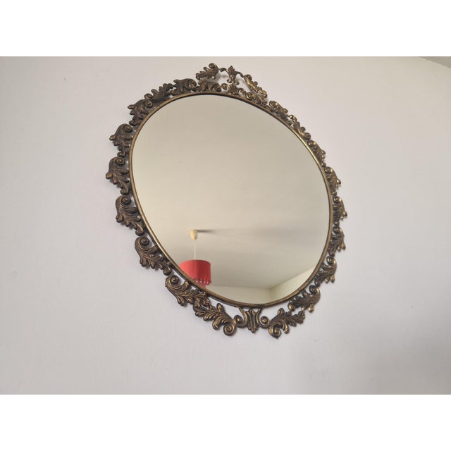 Elegant vintage wall mirror featuring an oval mirrored pane set in a finely crafted bronze openwork frame. The design...