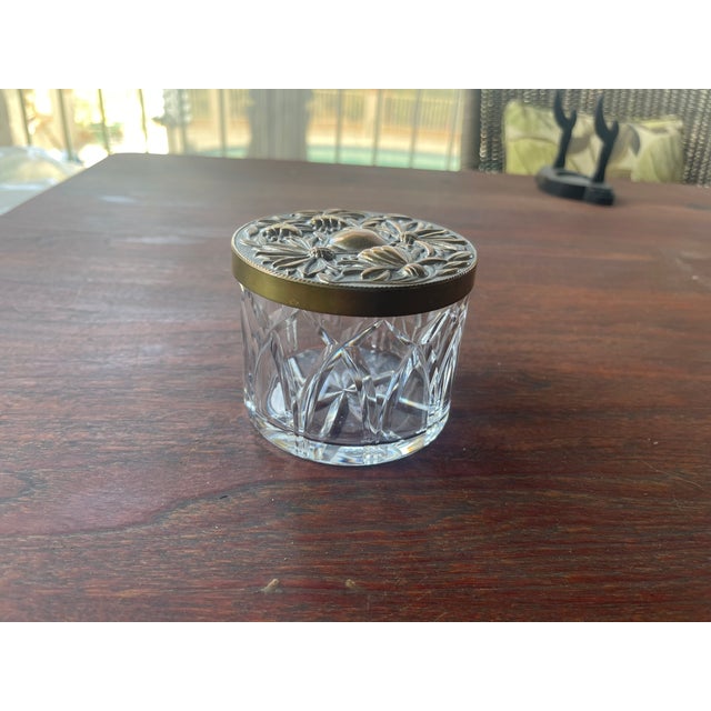 This item is an antique Art Nouveau vanity dresser jar featuring a decorative brass metal lid and a pressed glass base....