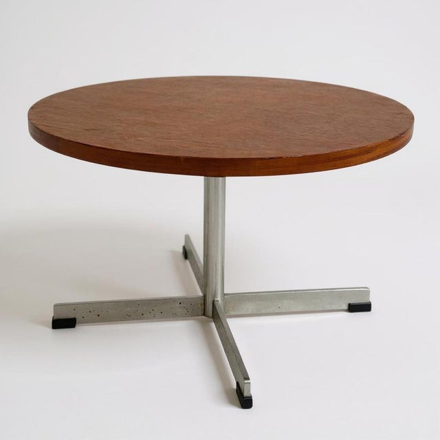 This mid century coffee table features a round teak top paired with a sleek chrome cross base, designed to bring vintage...