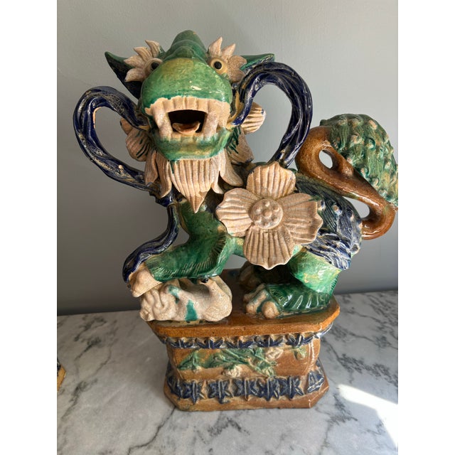 Gorgeous pair of large foo dogs in green and blue glaze from early 20th century. Made of terra cotta. Partial stamp on the...