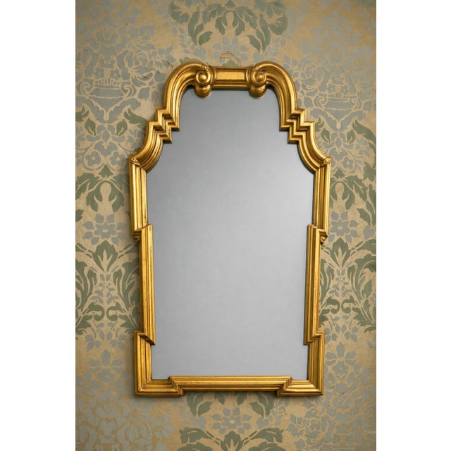 Elegant Italian-made gilt wall mirror featuring an arched silhouette with scrollwork, stepped corners, and a warm gold...