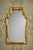 Elegant Italian-made gilt wall mirror featuring an arched silhouette with scrollwork, stepped corners, and a warm gold...