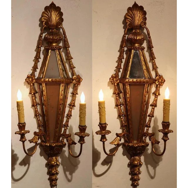 Elegant and architectural, this matching pair of antique French wall sconces combines carved giltwood, mirrored panels,...