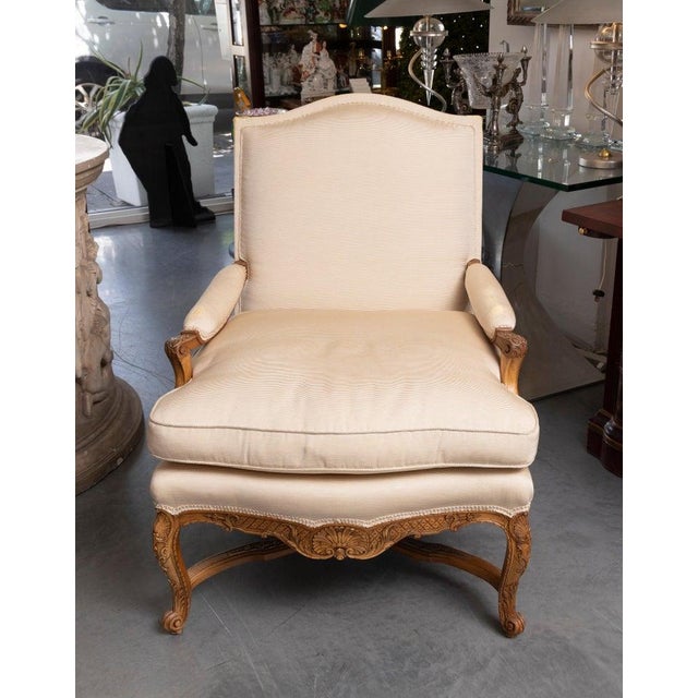 This is one of an elegant identical pair of French Louis XV-style arm chairs crafted in richly figured walnut with...