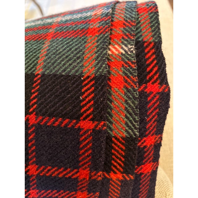 A classic tartan throw in deep navy, forest green, and black, crossed with bright red and fine white lines. It's woven in...