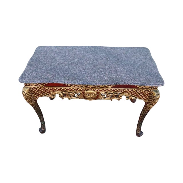 A striking Italian-style painted and parcel-gilt console table featuring an elegant marble top and richly carved...