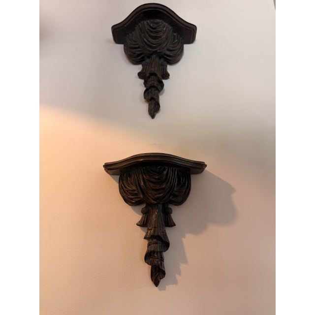 Pair of mid-century, Hollywood Regency style wall-mounted shelves featuring intricate detailing throughout. Trompe l’Oeil,...