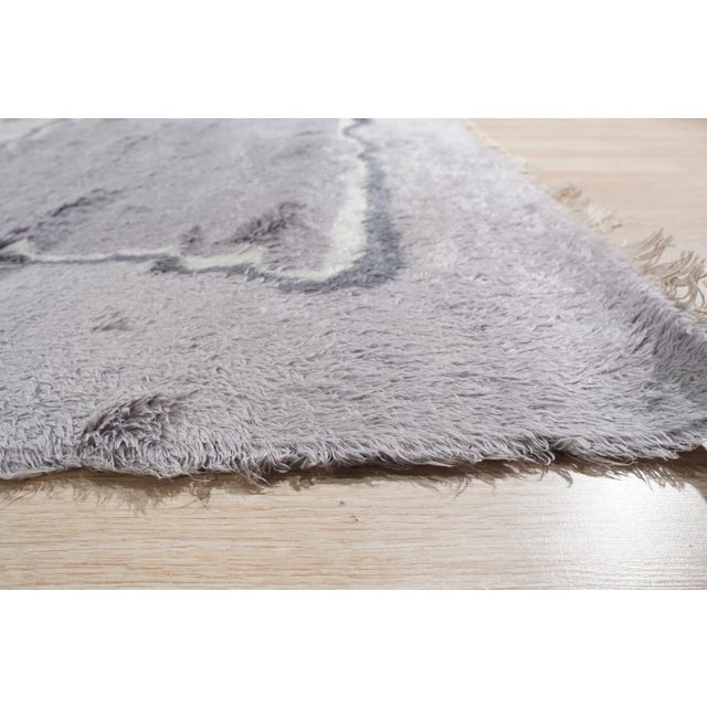 A hand-knotted wool rug, made in India and measuring 5' x 8'. Loose, abstract drawing rather than a formal repeating...