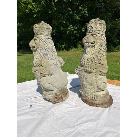 A matching pair of vintage cast concrete lion statues bearing armorial decoration.