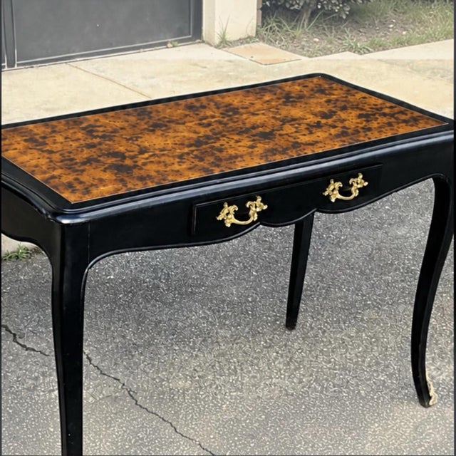 This is a French Louis XIV style desk with a faux tortoise finished top. The desk is marked. The antique hardware is gilt...