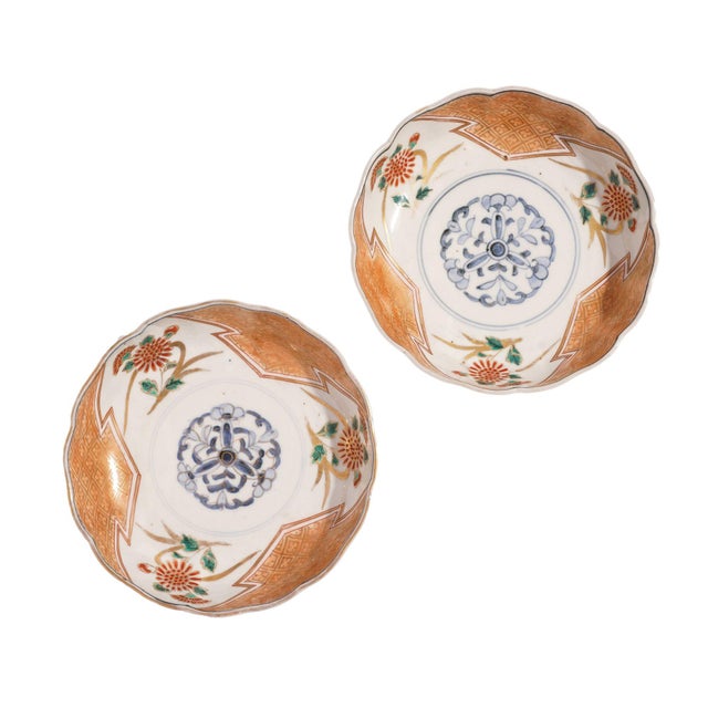 Pair of Japanese porcelain footed bowls in red, green, and blue, highlighted with gold decoration. The decoration centers...