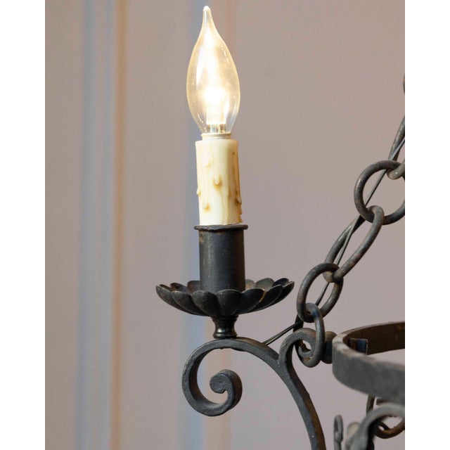 A refined 20th-century French wrought iron chandelier featuring elegant craftsmanship and a graceful, architectural...