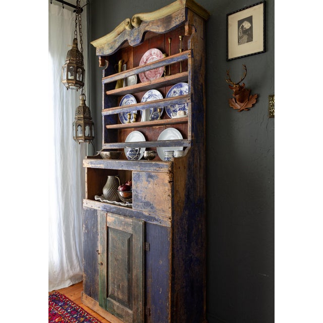 A primitive 19th-century Romanian step-back cupboard retains its original blue paint and the number '88' in the middle of...