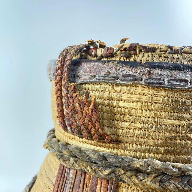 Handwoven storage vessel attributed to the Luo people of East Africa. This sculptural basket features a tightly coiled...