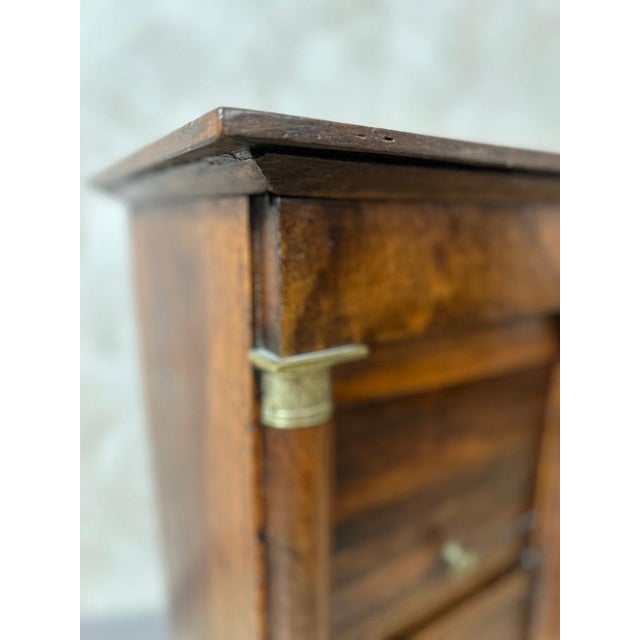 Charming Empire period bedside table in walnut, resting on two columns with bronze or brass rings, typical of the style....