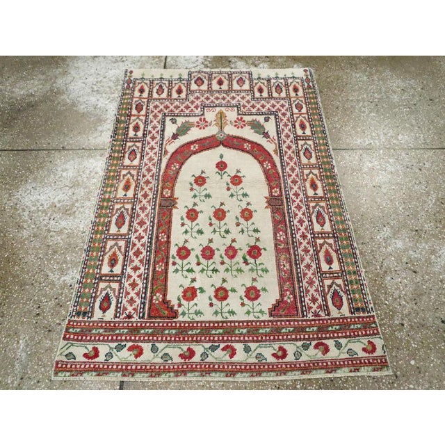 A vintage Indian Cotton Agra throw rug. A columnar pointed arch encloses 13 identical flowering plants and is itself...
