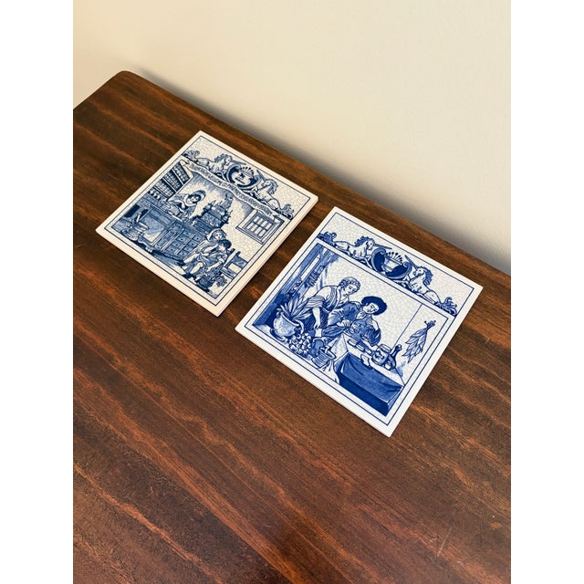 A classic pair of Dutch Delft-style hand painted blue and white porcelain tiles featuring medical scenes of an herbalist...