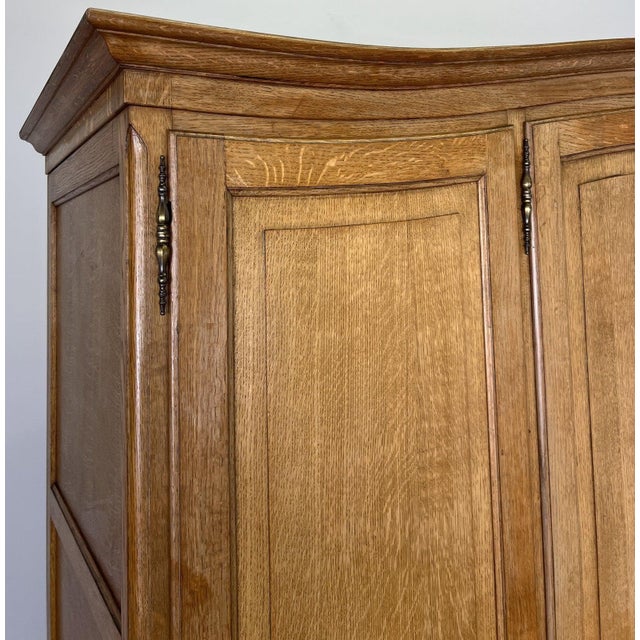 An elegant Vintage French Louis wardrobe crafted from oak, featuring a refined four door design with softly shaped panels,...
