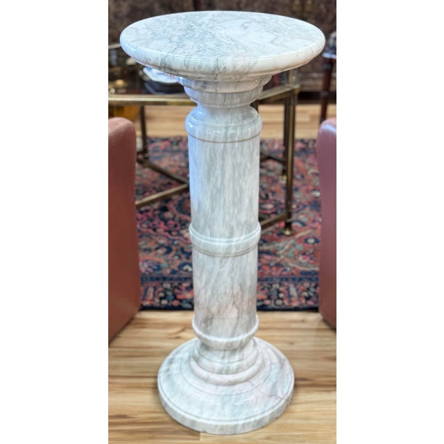Vintage white and gray veined marble column pedestal featuring straight column resting on a round base with additional...
