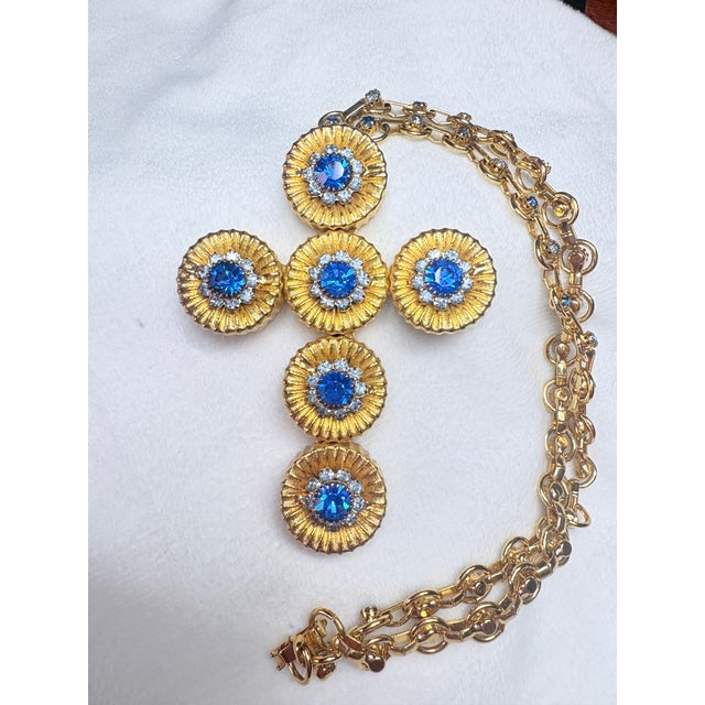 Vintage Alexis Kirk necklace featuring sculptural gold‑tone sunburst elements set with faceted blue stones and bright,...