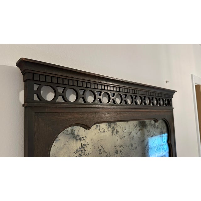 Vintage decorative wall mirror featuring a richly stained dark walnut-toned wood frame and beautifully antiqued mirror...