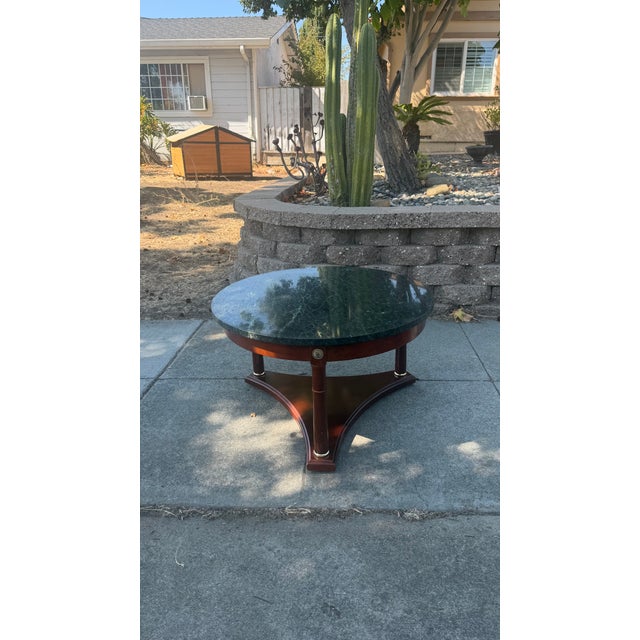 This Vintage French Empire Neoclassical Style Mahogany Green Marble Top Coffee Table is a striking piece that exudes...