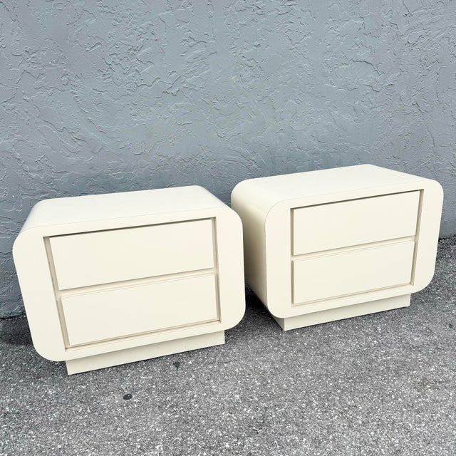 A striking pair of postmodern waterfall nightstands defined by soft rounded edges and a smooth cream gloss laminate...