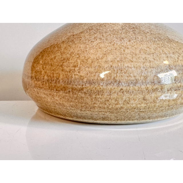 A handcrafted and signed studio-ceramic vase from the 1970s, featuring a harmoniously rounded shape, a slender neck, and a...
