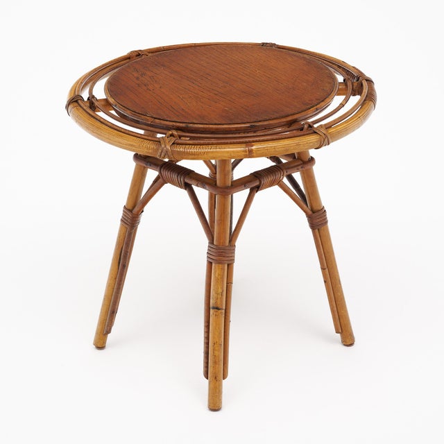 Side table from Vallauris, France made of bamboo. There is a circular wood top with a curved bamboo structure. This piece...