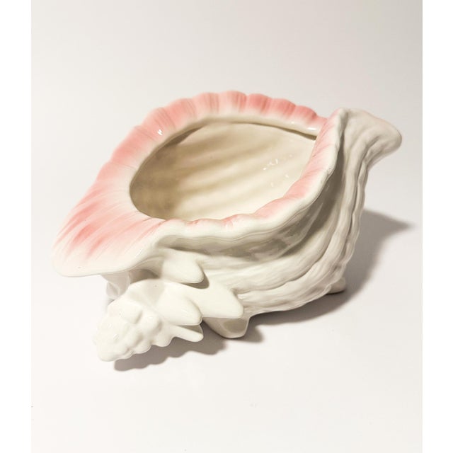 This charming vintage ceramic cachepot, shaped like a majestic conch shell, will add a touch of timeless coastal elegance...