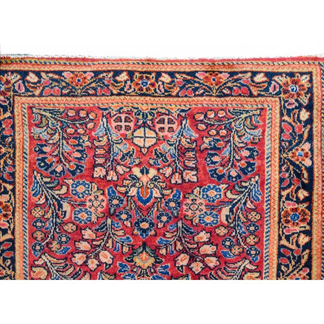 A beautiful early 20th century Persian Sarouk rug with a mirrored floral pattern woven in pink, light and dark indigo,...