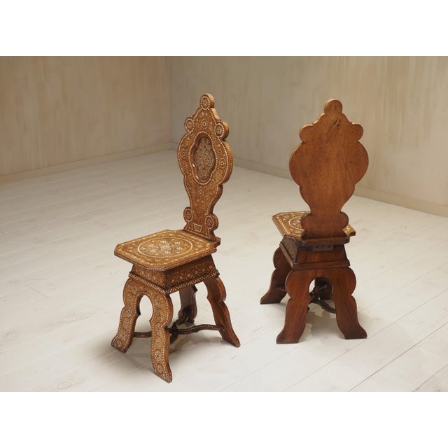 Renaissance revival elegance, this exceptional pair of 19th-century sgabello hall chairs, expertly crafted in richly...