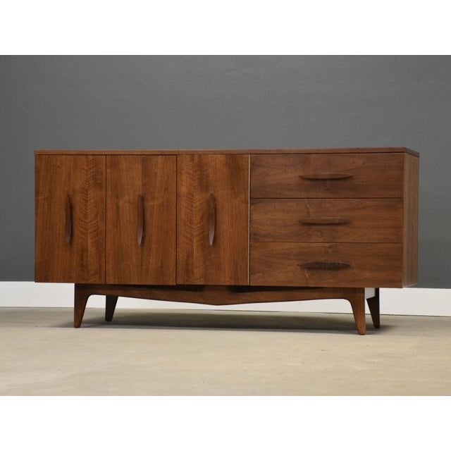 A mid century modern walnut credenza with sculpted pulls made by Young Furniture. Professionally refinished. Circa 1960....