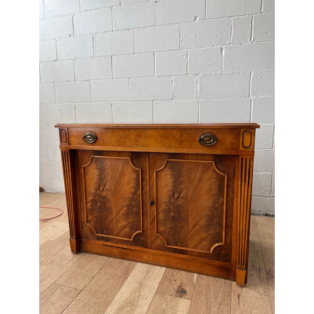 A distinguished extending sideboard cabinet by the renowned Saginaw Furniture Company, crafted in richly figured mahogany...