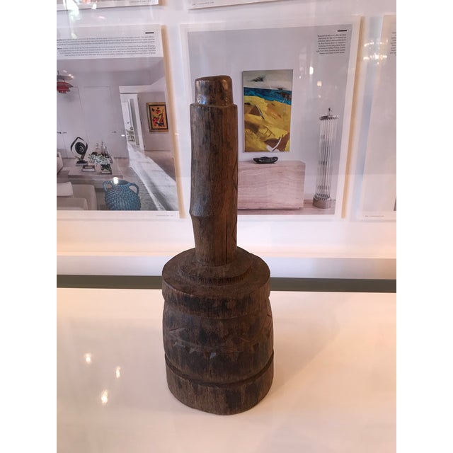 Hand-carved wood implement with carved designs on it. The handle has a placement for the thumb separating the fingers for...