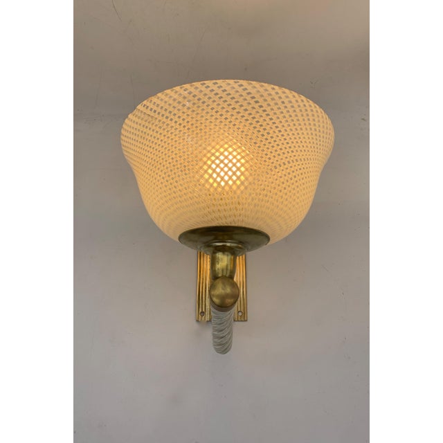 A pair of elegant, vintage-style wall lamps, attributed to Venini, each composed of a large, conical, blown milky glass...