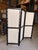 Contemporary room divider featuring a bold black wood frame with handwoven cream leather panels that create a striking...