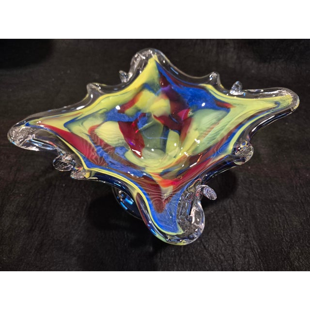 This is an organic, multi-pointed Murano style art glass bowl featuring a splash of vibrant colors encased in clear glass....