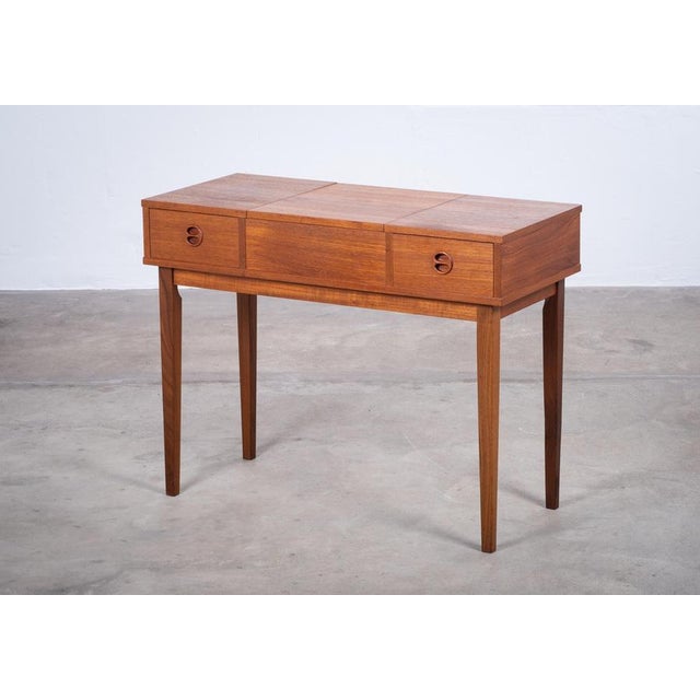 Elegant teak vanity table produced in Denmark during the 1960s. Featuring two drawers and a central mirror, this versatile...