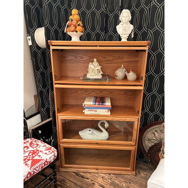Handsome vintage 4 tier wooden and glass barrister or lawyer bookcase with front lift up doors and a golden oak finish....