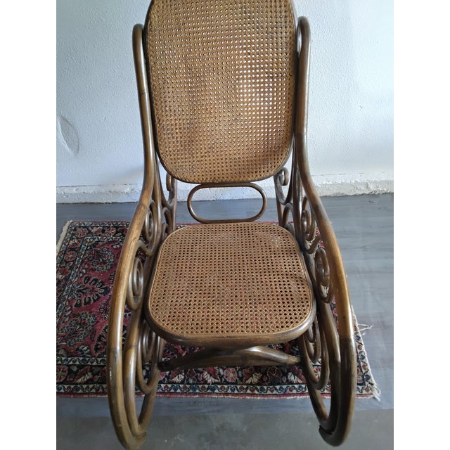 Description A striking vintage bentwood rocking chair featuring woven cane seat and back panels and elaborate scrolling...
