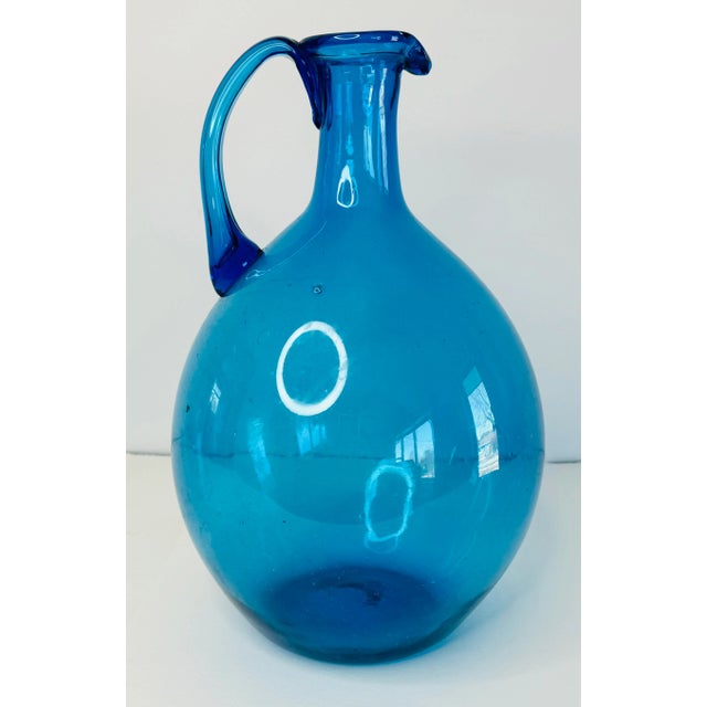 Vintage 1960s Blenko Style Blue Glass Jug with an applied handle and a rolled lip. Beautiful classic blue color, this jug...