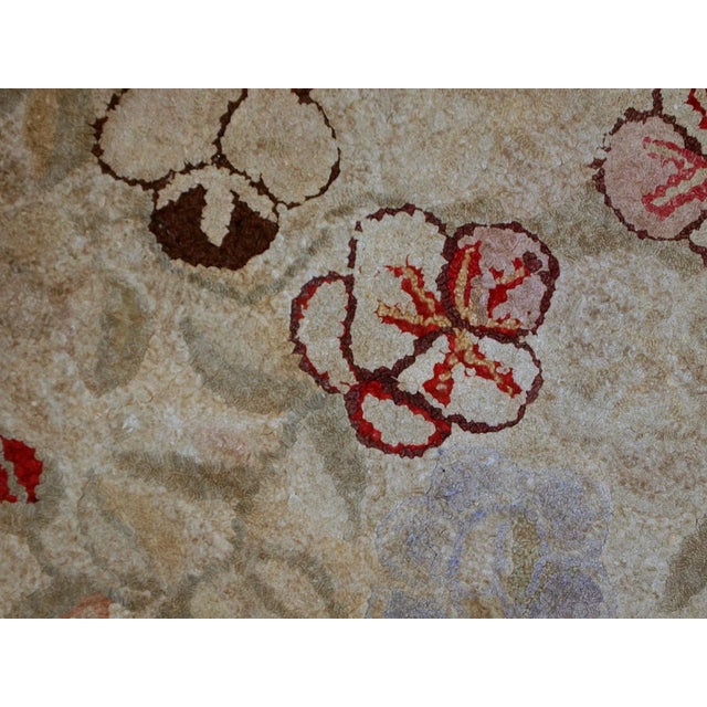 Handmade antique American Primitive Hooked rug in beige shade with abstract/floral design. The border is purple. It is in...