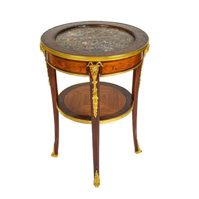 This elegant French round side table exemplifies the refined craftsmanship and luxurious materials associated with early...